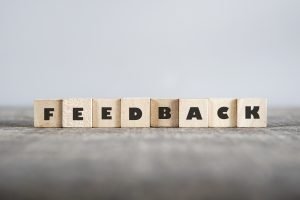 Feedback written in wooden blocks against a grey background.