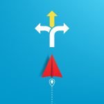 Red paper aeroplane on a blue background facing towards a crossroads